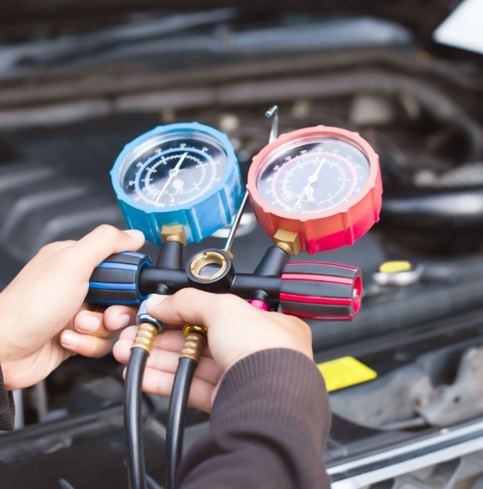 mechanic testing ac system with tool